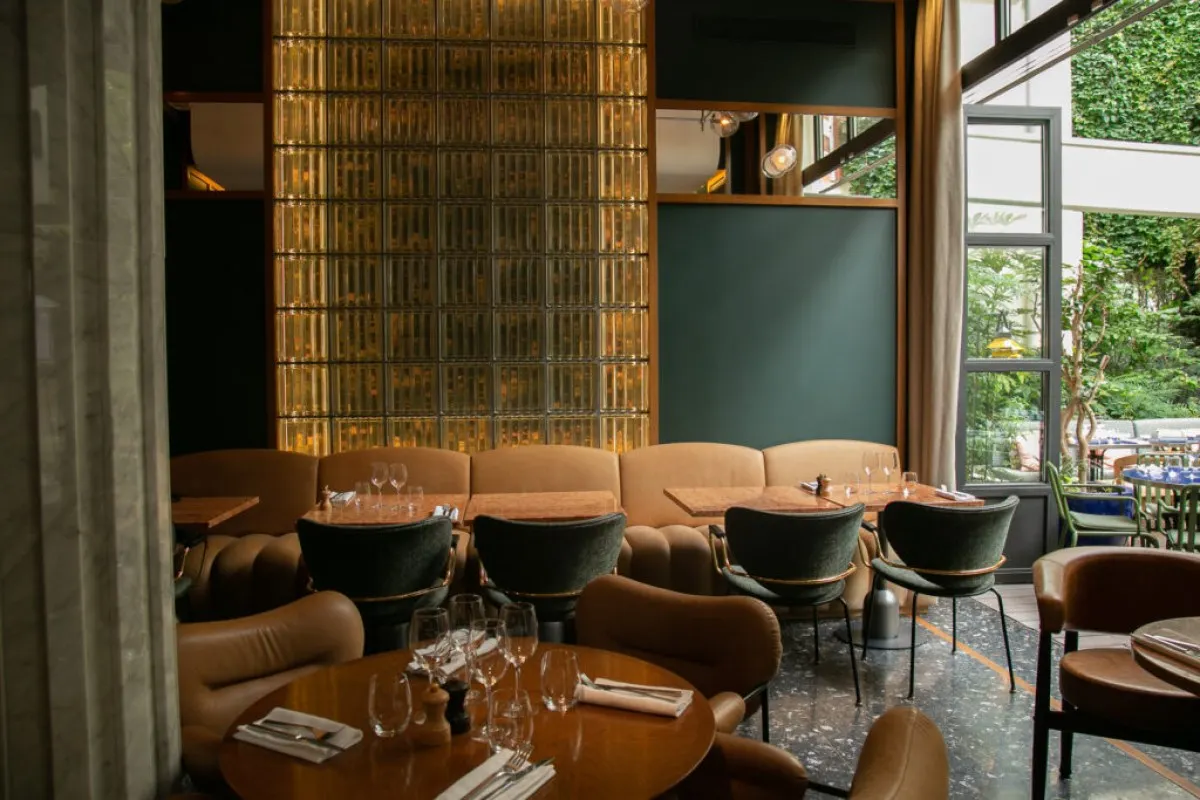 Hotel restaurant with leather chairs, wooden tables, glass-block feature wall and garden view