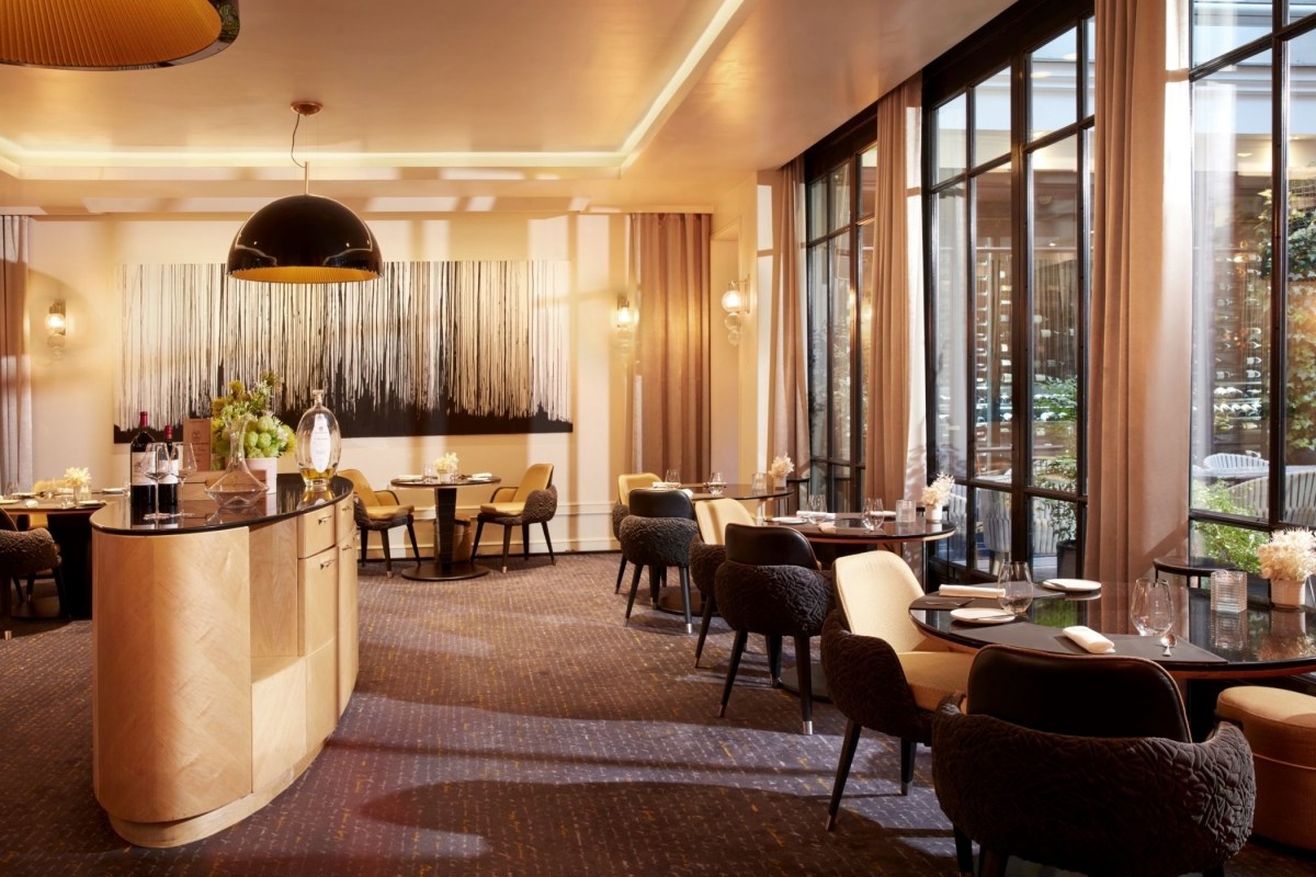 Elegant dining room with round tables, patterned chairs, and large windows to garden terrace