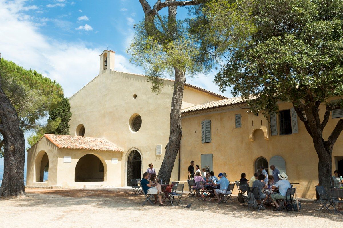 Café tables of Le Bistrot du Curé in the shade of the pines beside the chapel of Notre-Dame-de-la-Garoupe on the Garoupe plateau, Cap d'Antibes