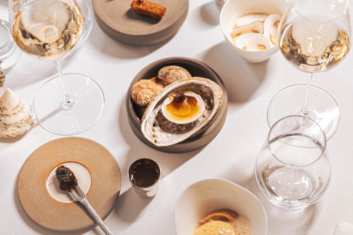 Overhead shot of seafood dishes and shells with wine glasses on white tablecloth