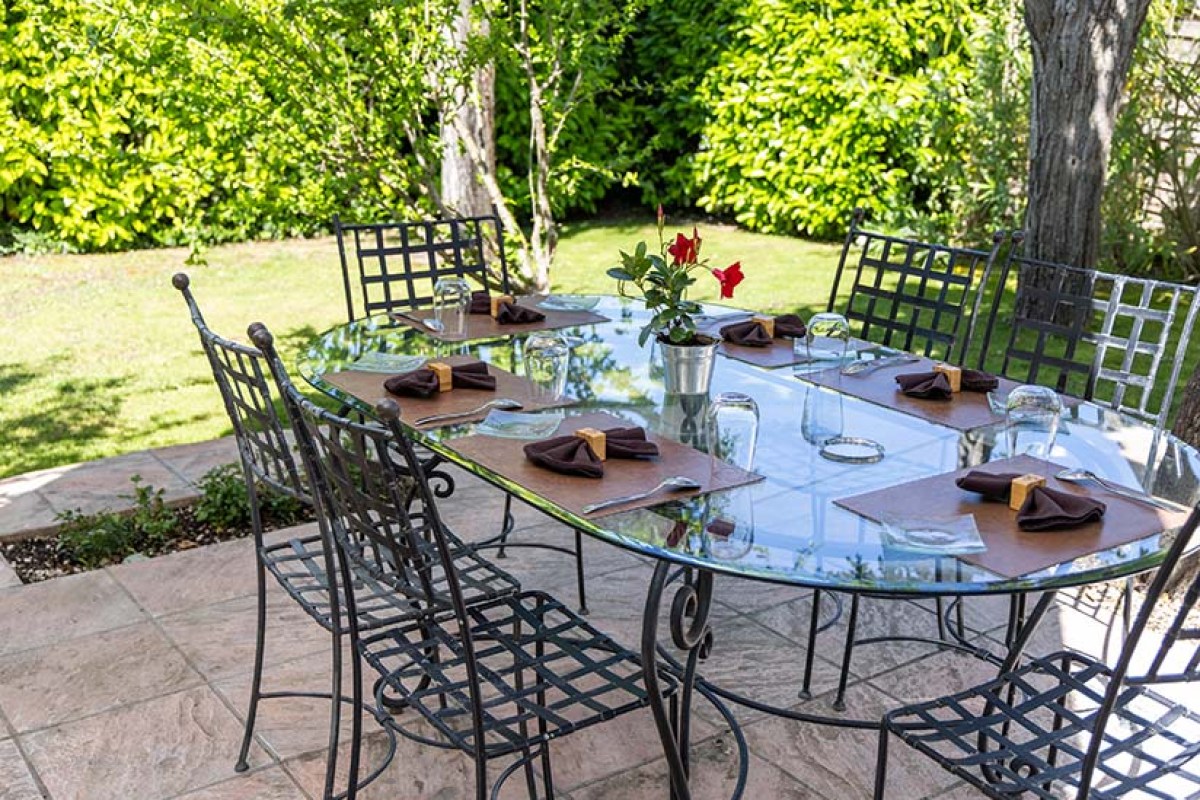 Outdoor terrace dining table set with place settings in a garden setting at Le Carré d'Ange