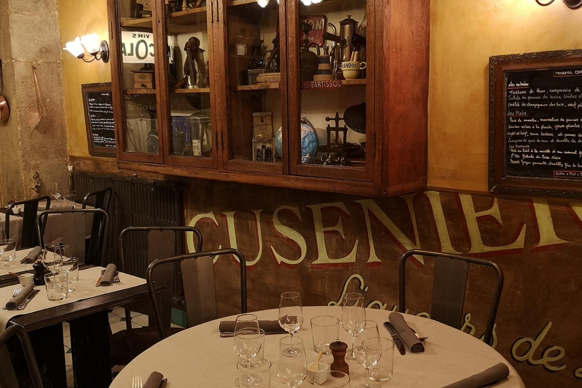 Cozy vintage-style dining room with set tables, wooden cabinet of curios, and chalkboard menus on the wall