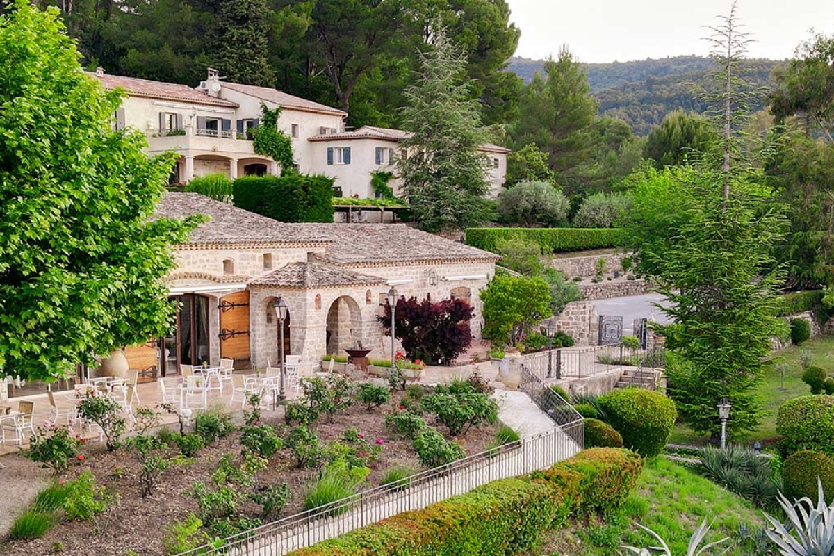 Aerial view of Le Castellaras stone building with terrace, gardens and surrounding hills