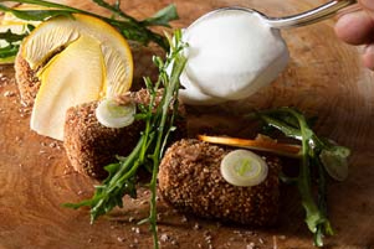 Plated dish with crumbed croquettes, arugula, lemon and a quenelle of sauce