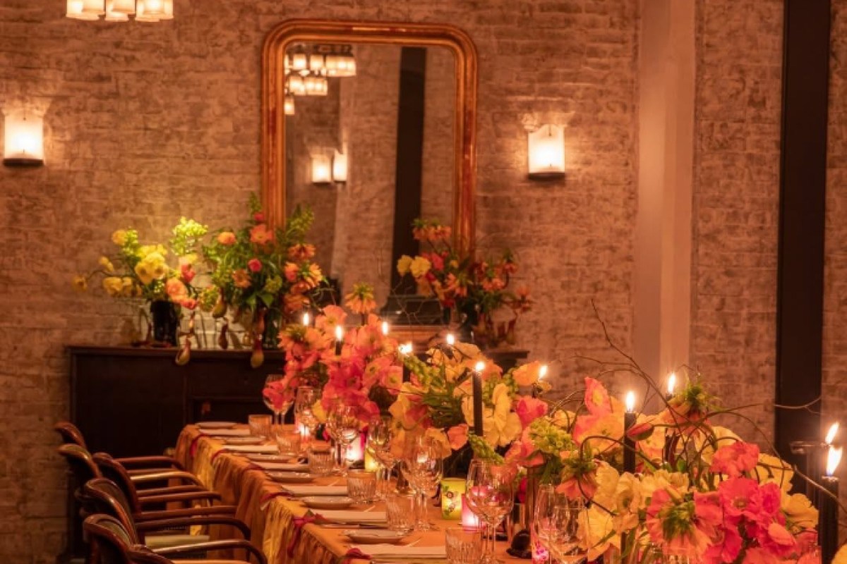 Long candlelit table with floral arrangements in a private dining room at Le Coucou