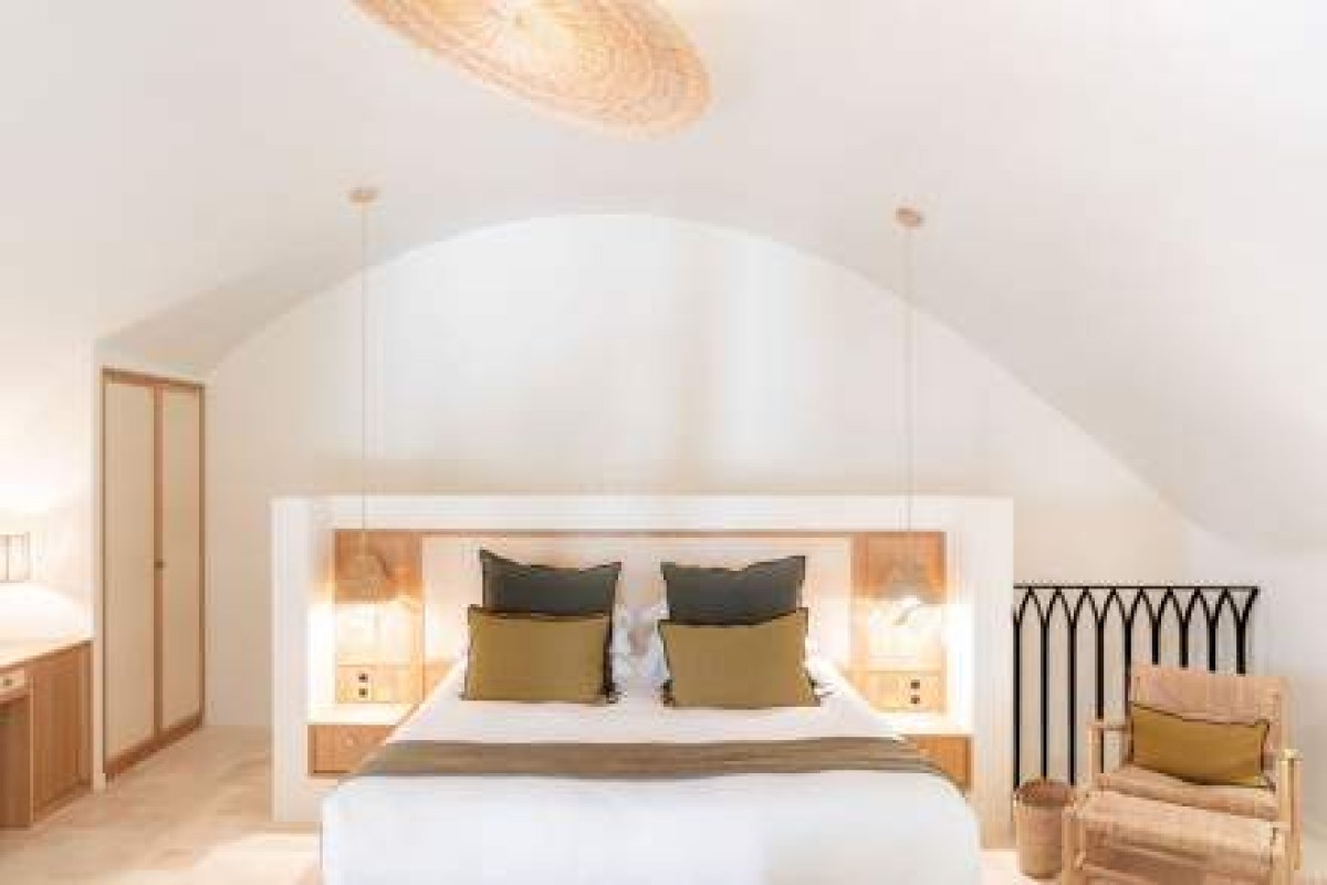 Guest room with vaulted ceiling, bed with green and gold pillows