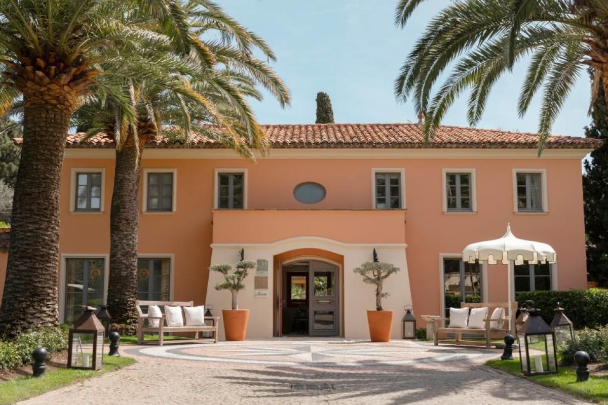Exterior view of the peach-colored villa facade with palm trees and entrance driveway