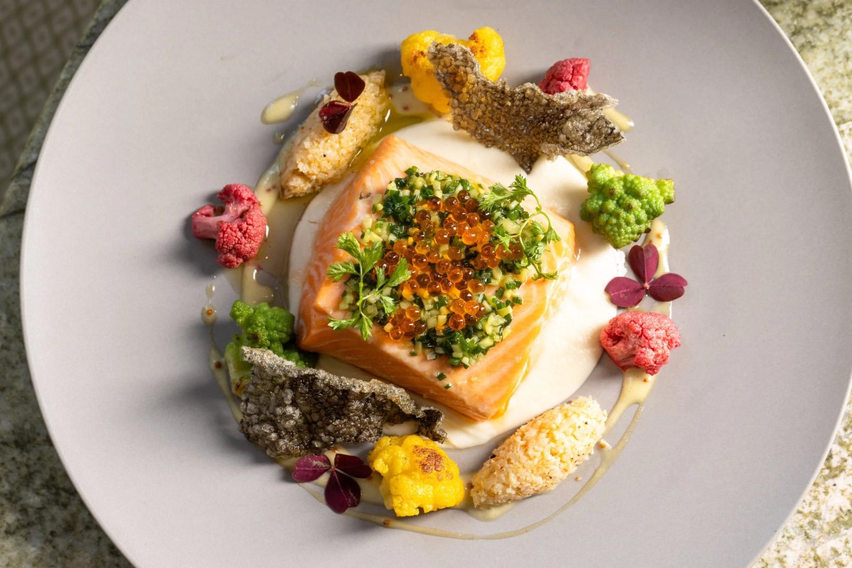 Plated salmon dish with caviar, herbs, cauliflower florets, and crispy tuile garnishes