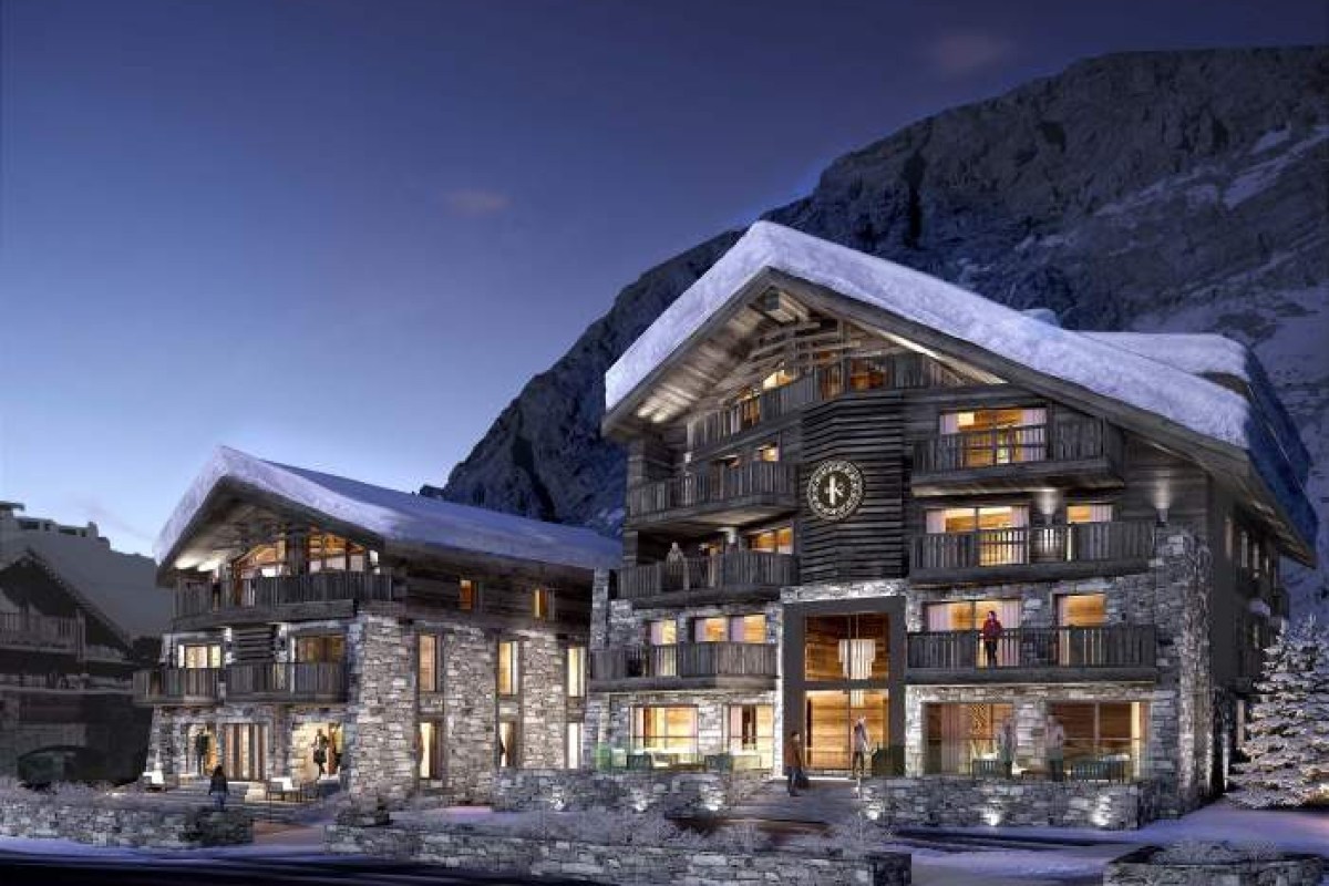 Evening exterior view of Le K2 Chogori hotel's stone and wood chalet facade lit up against a mountain backdrop.