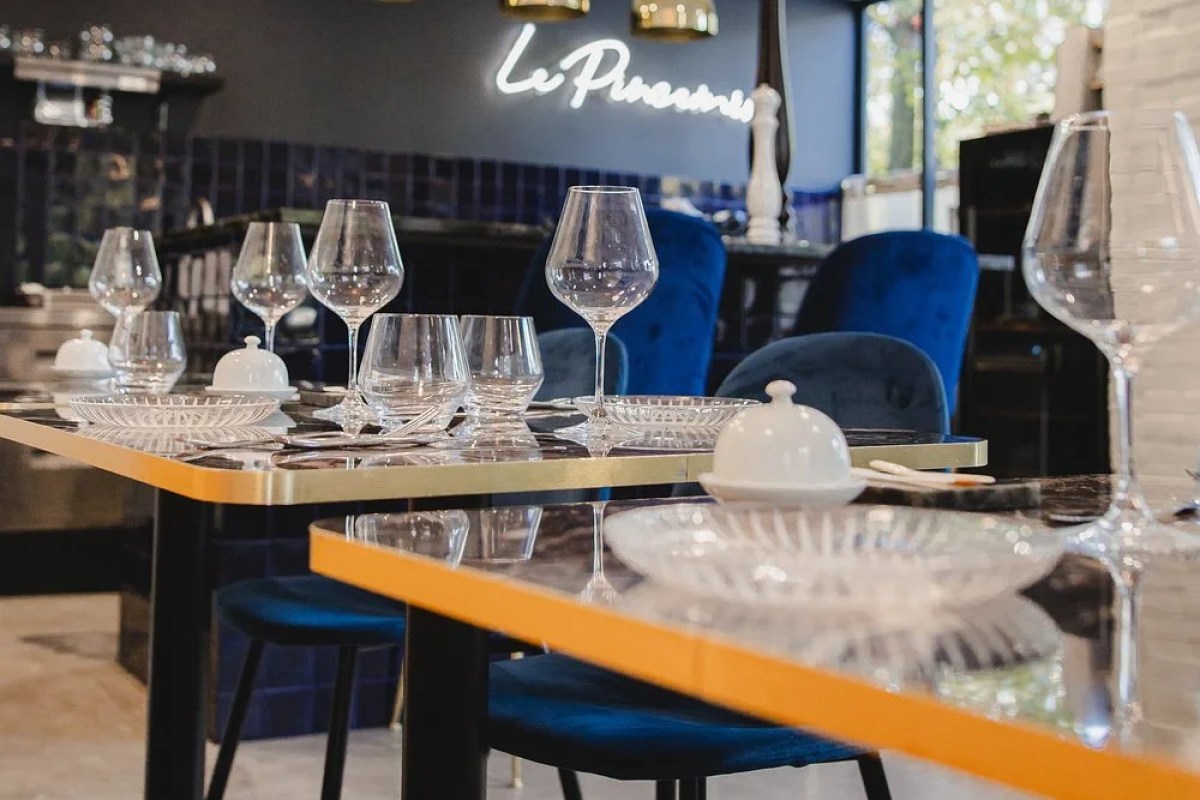 Le Pincemin dining room with illuminated restaurant sign, blue velvet chairs and an elegantly set table with glassware