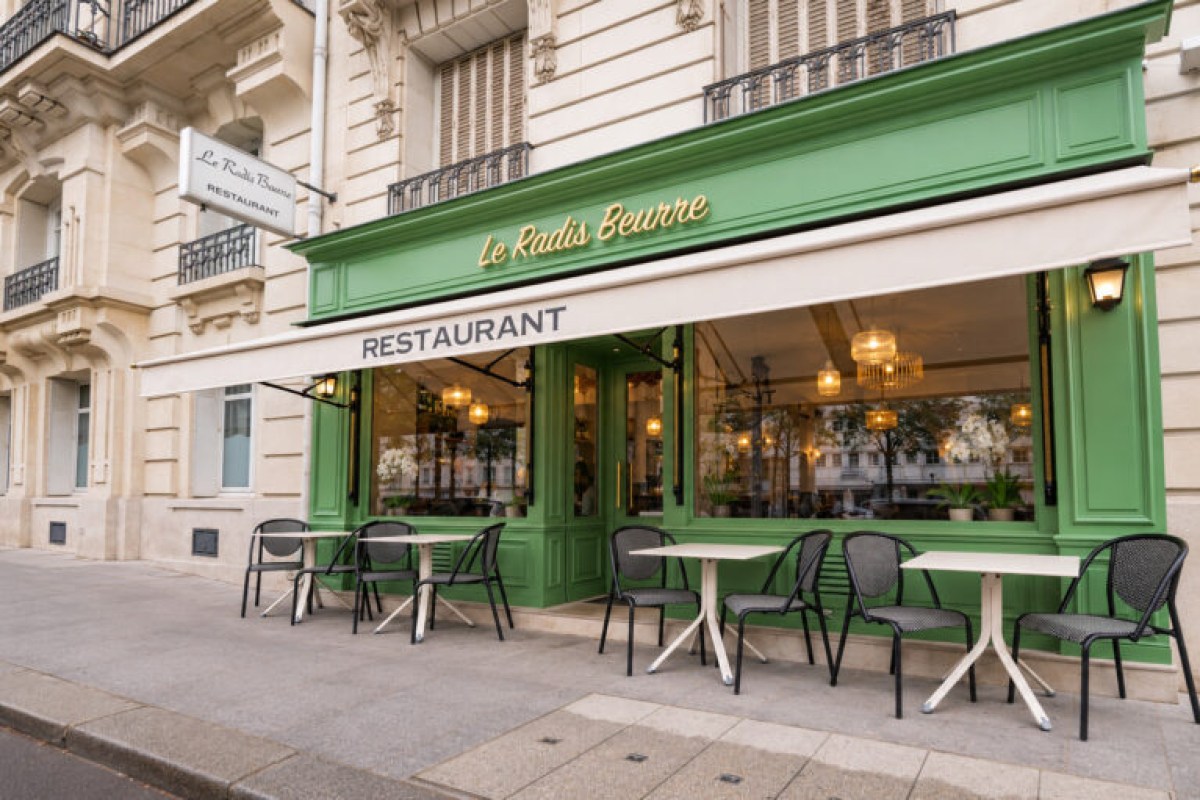 Exterior of Le Radis Beurre restaurant with green facade, terrace tables and chairs on the sidewalk