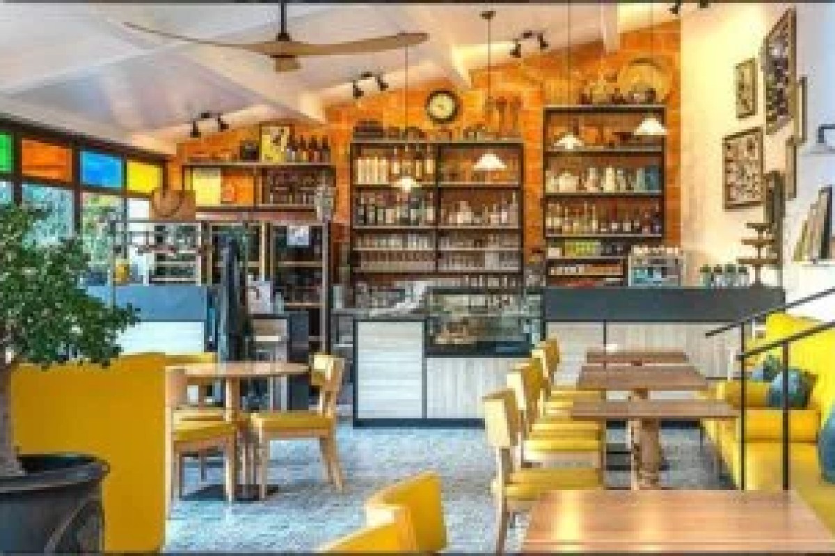 Interior bar/dining area with yellow chairs, shelves of bottles and brick wall