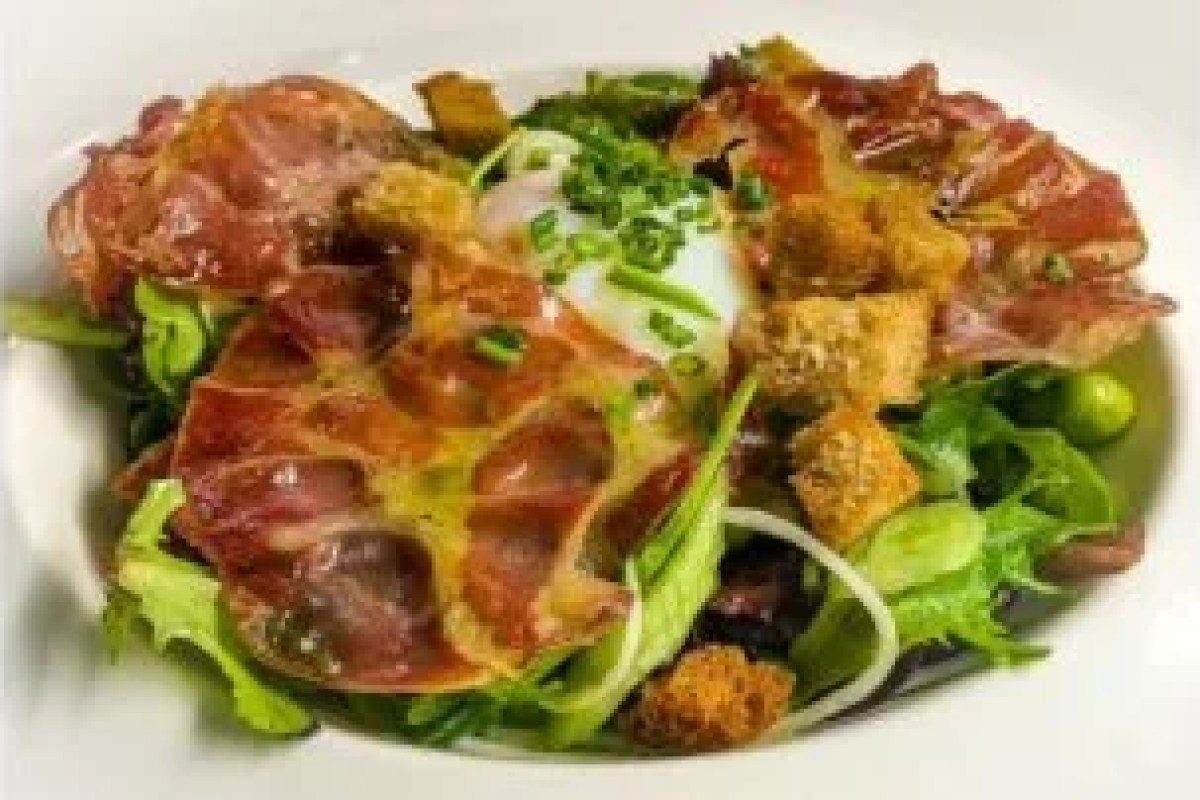 Plated dish with crispy ham, poached egg, greens and croutons