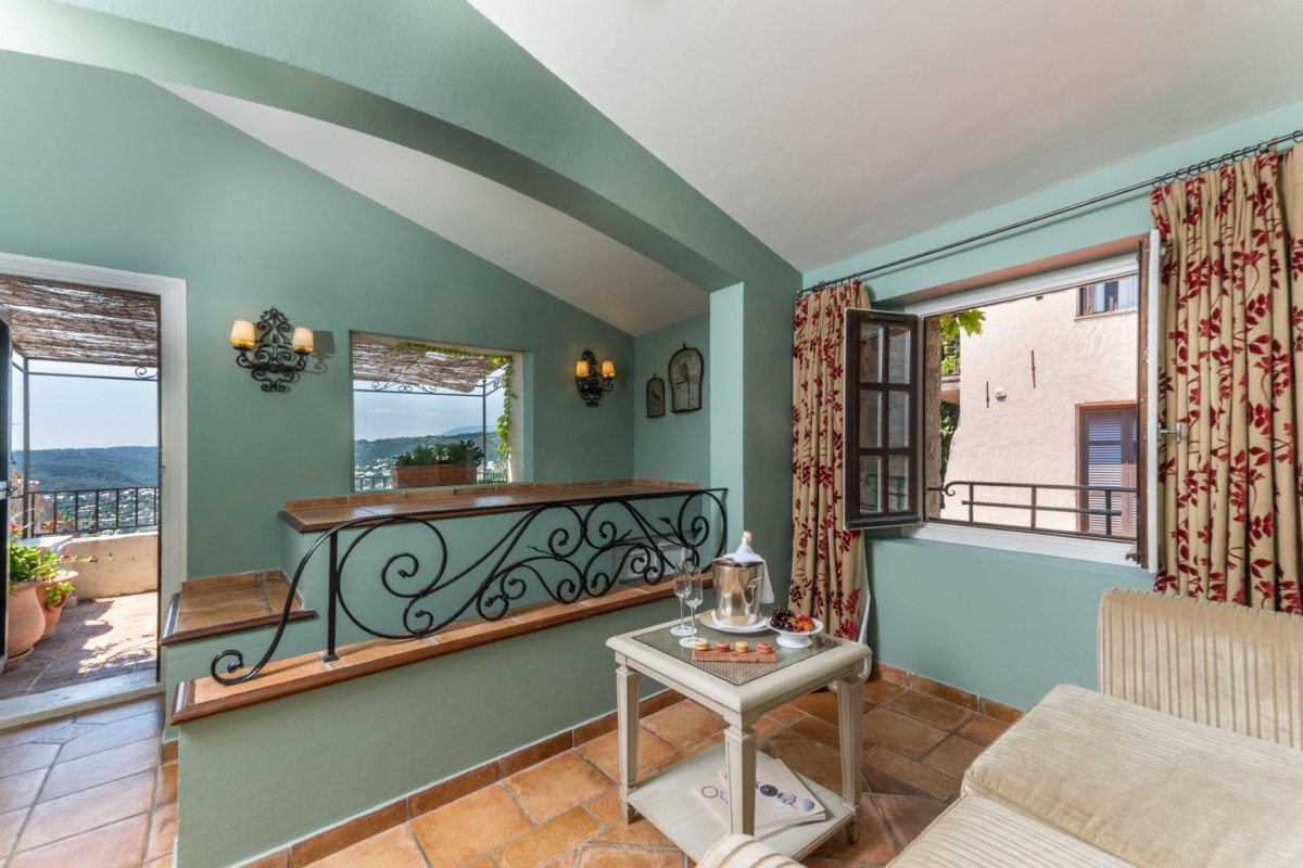 Cozy lounge area with sage-green walls, wrought-iron balustrade and terrace view