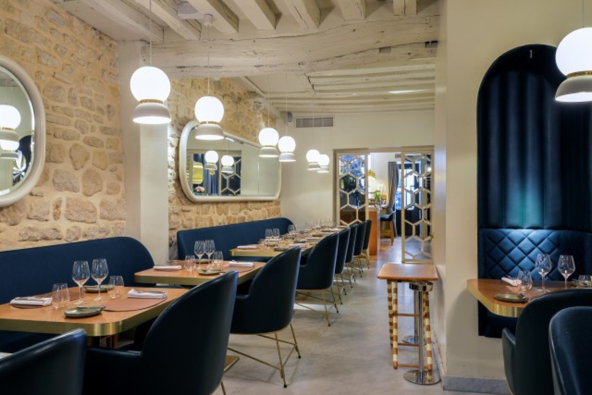 Dining room with stone wall, exposed beams, blue banquette seating and globe pendant lights