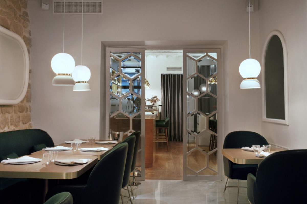 Dining room with dark green booth seating, globe pendant lights and hexagonal mirrored doors