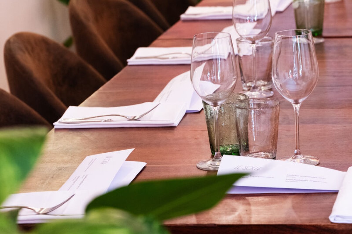Laid table at Le Socle with wine glasses, folded napkins and menus on wood table