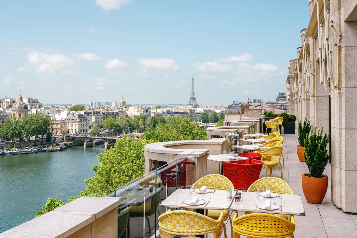 Rooftop terrace with yellow and red chairs along the Seine, Eiffel Tower visible in distance