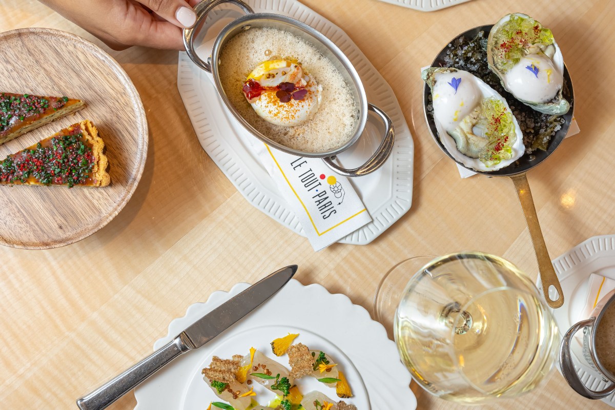 Overhead shot of oysters, seafood dish, and tart with Le Tout-Paris branded napkin