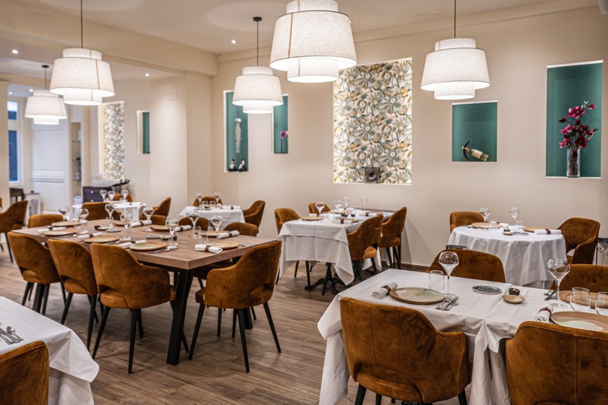 Elegant restaurant dining room with white tablecloths, velvet chairs, and pendant lighting