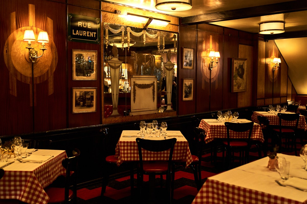 Le Veau d'Or dining room with checkered tablecloths, red banquettes, Art Deco mirror and 'Rue Laurent' sign