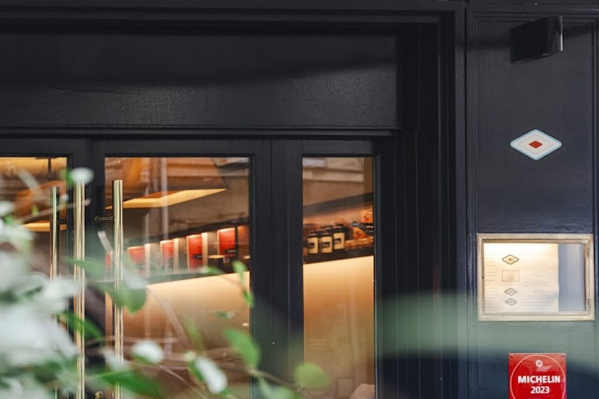 Exterior entrance of Le Violon d'Ingres with dark façade, glass doors, and Michelin 2023 plaque.