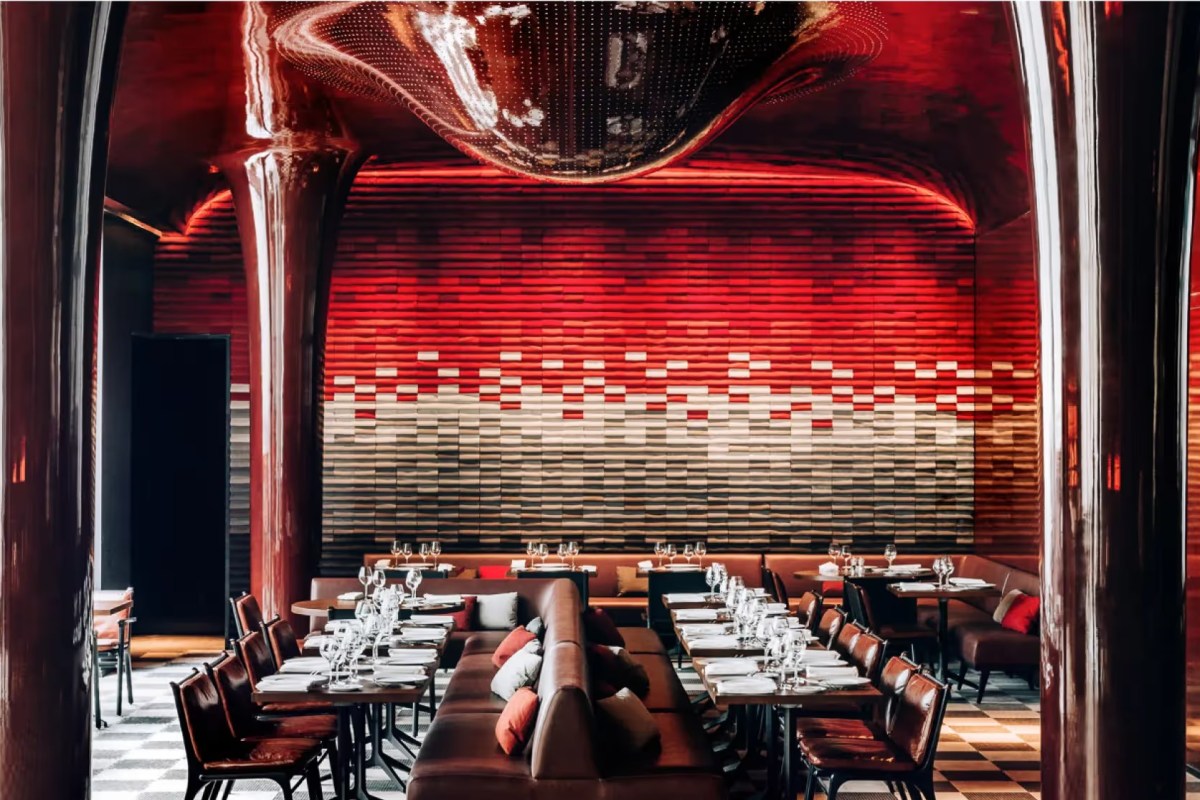 Red-toned restaurant with disco ball ceiling, checkerboard floor and leather banquettes