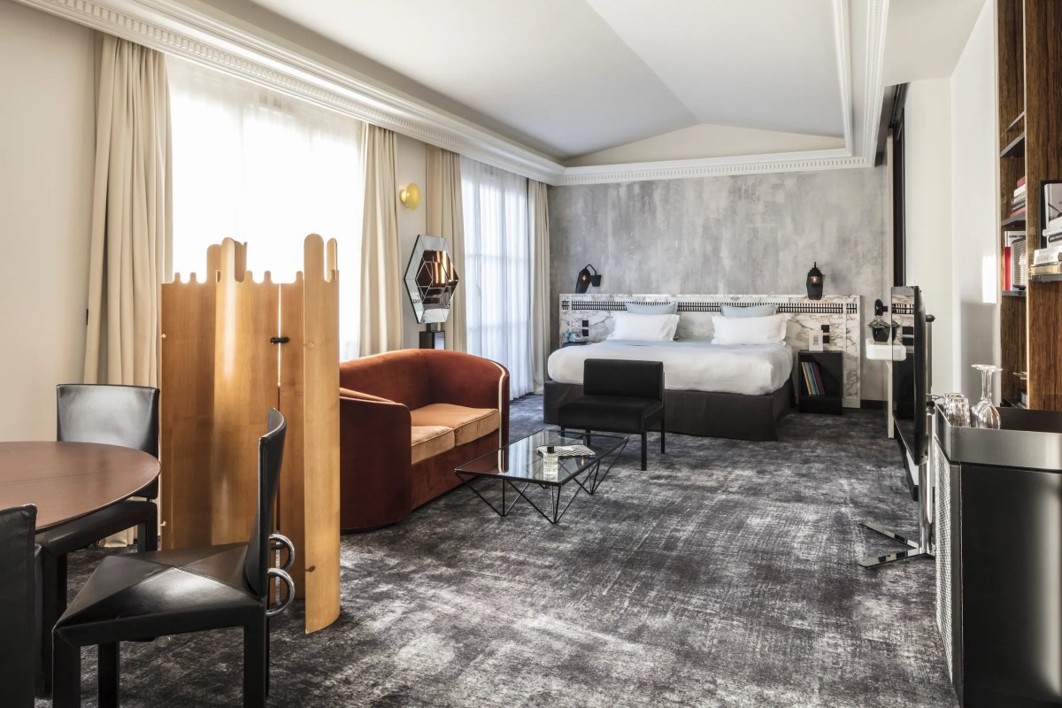 Spacious suite with bed, velvet sofa, wooden room divider and dining table