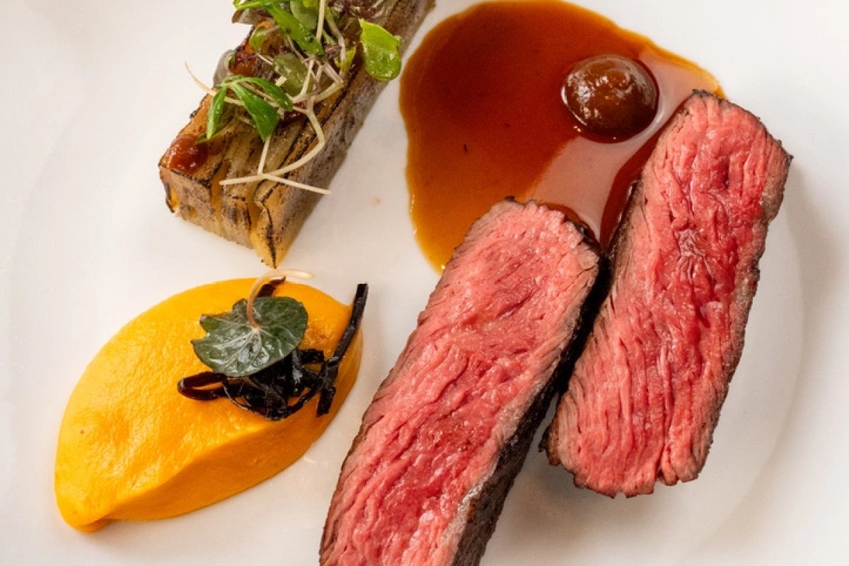 Plated gourmet dish: sliced rare beef with brown sauce, bone marrow toast, and carrot purée on a white plate
