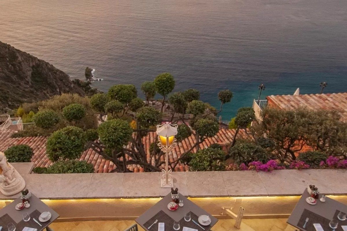 Restaurant terrace tables overlooking the Mediterranean coastline at dusk, Èze