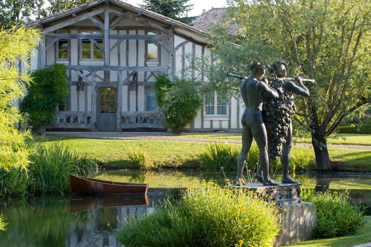 Half-timbered hotel building with pond, statue and wooden rowing boat in foreground