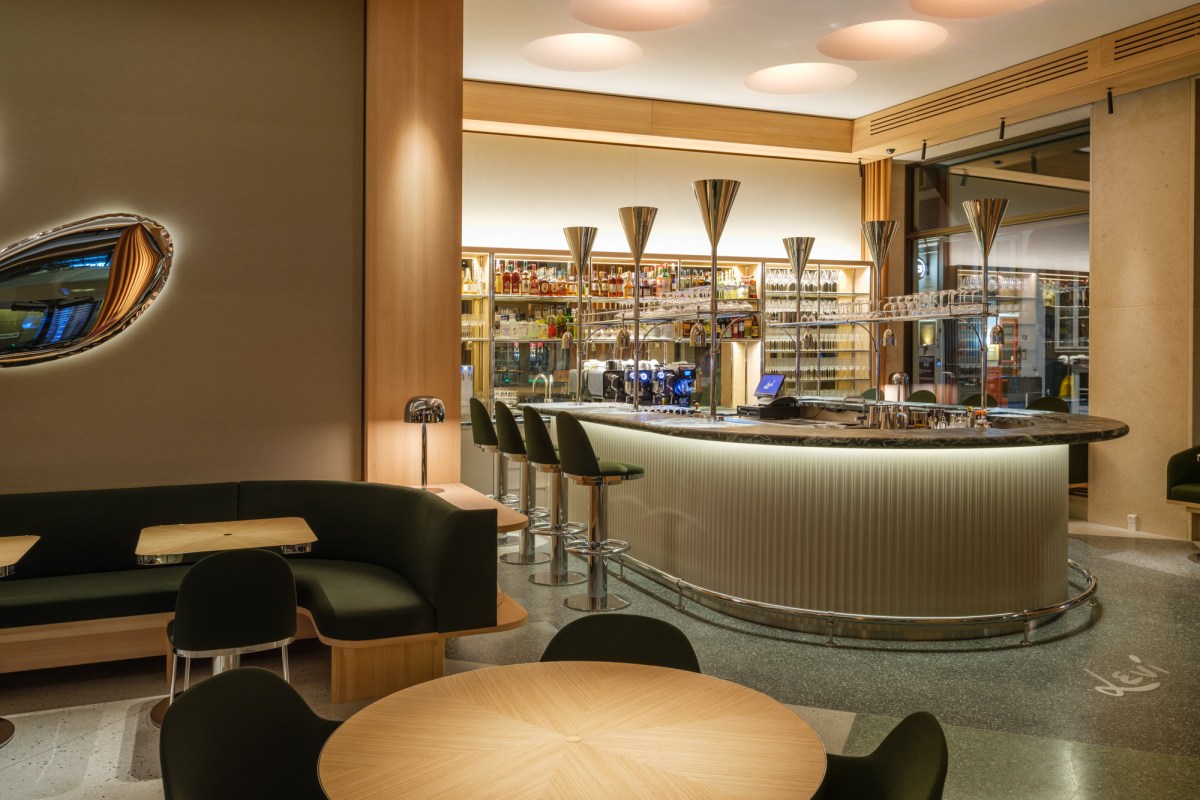 Interior view of Levi restaurant showing a curved bar with stools, green banquette seating, and round wooden tables