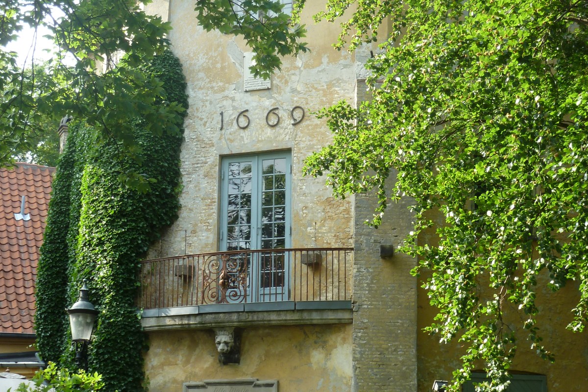 Close-up of Lille Mølle's tower facade with balcony, wrought-iron railing, and the inscribed date 1669.