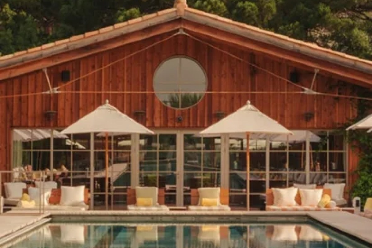 Exterior of Lily of The Valley's wood-clad building with pool and umbrellas in front