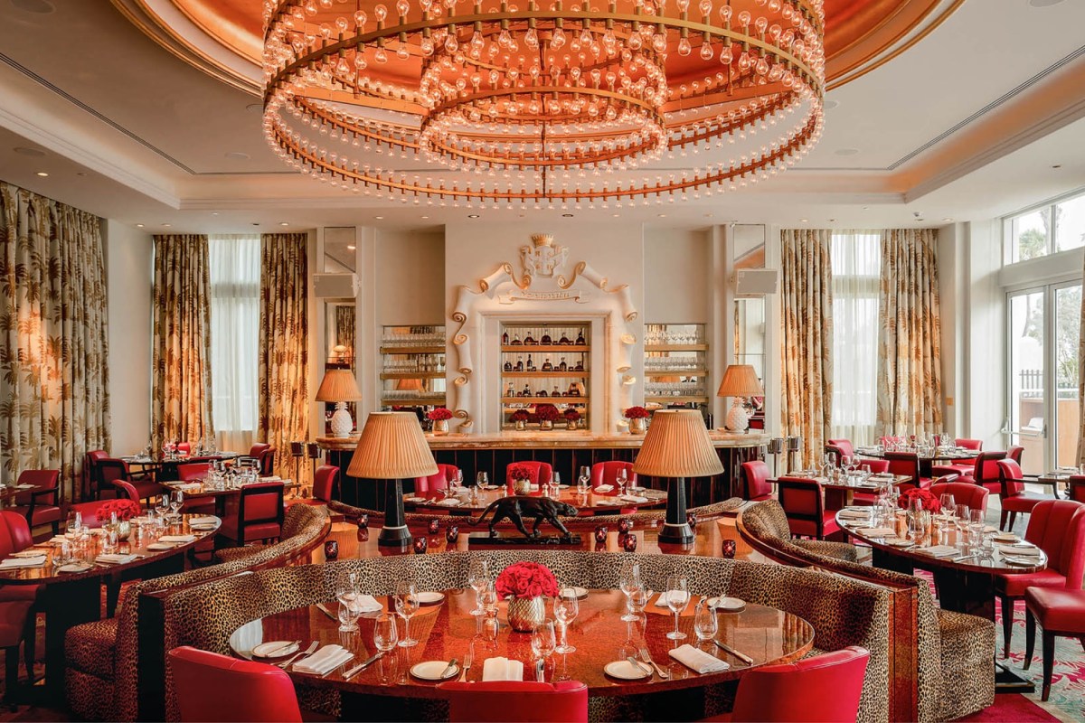 Elegant dining room with red leopard-print booths, chandelier, and bar area