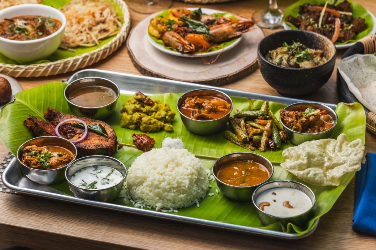 Full banana leaf thali spread with rice, fish, shrimp, curries, papadum and chutneys on a steel tray