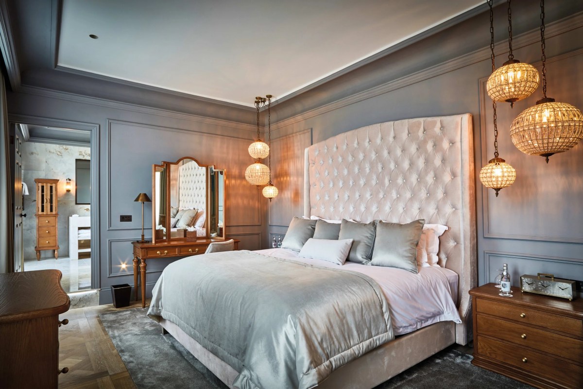 Elegant hotel suite with tufted headboard, crystal pendant lights and dressing table