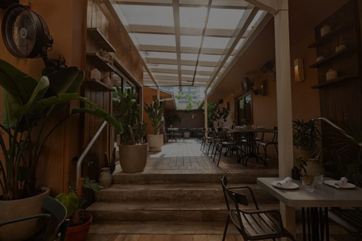 Open-air restaurant terrace with potted plants, skylight roof, and dining tables