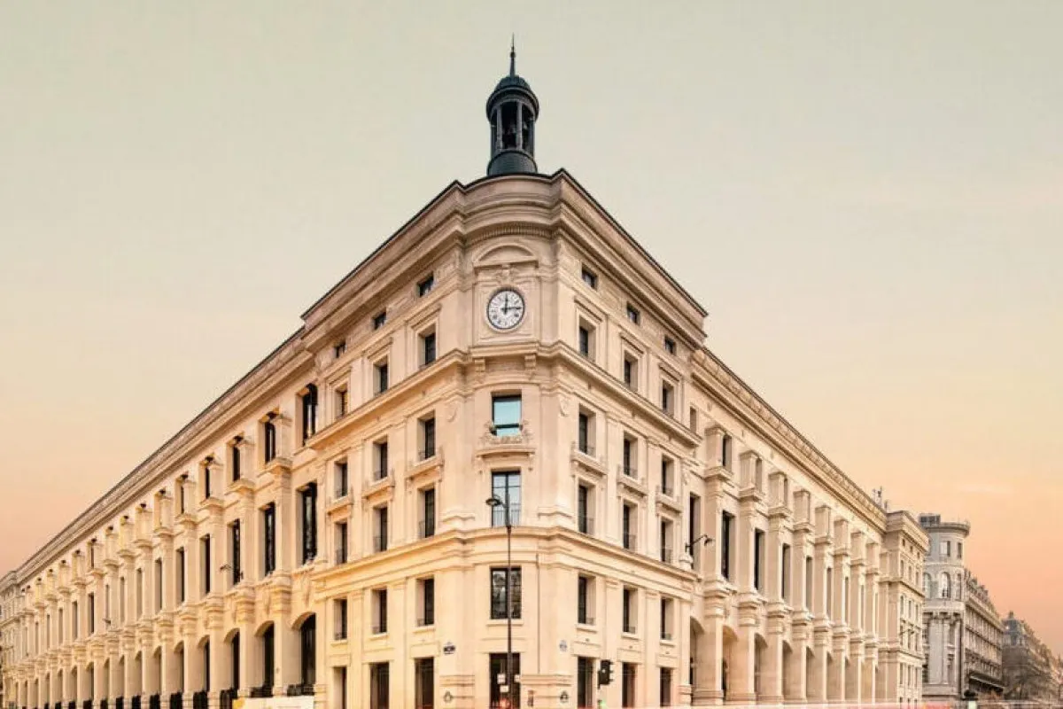 Corner view of Madame Rêve's ornate Haussmannian façade at dusk, clock tower visible