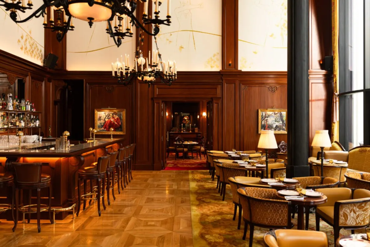 Elegant wood-paneled bar and restaurant with chandeliers, bar stools and dining tables