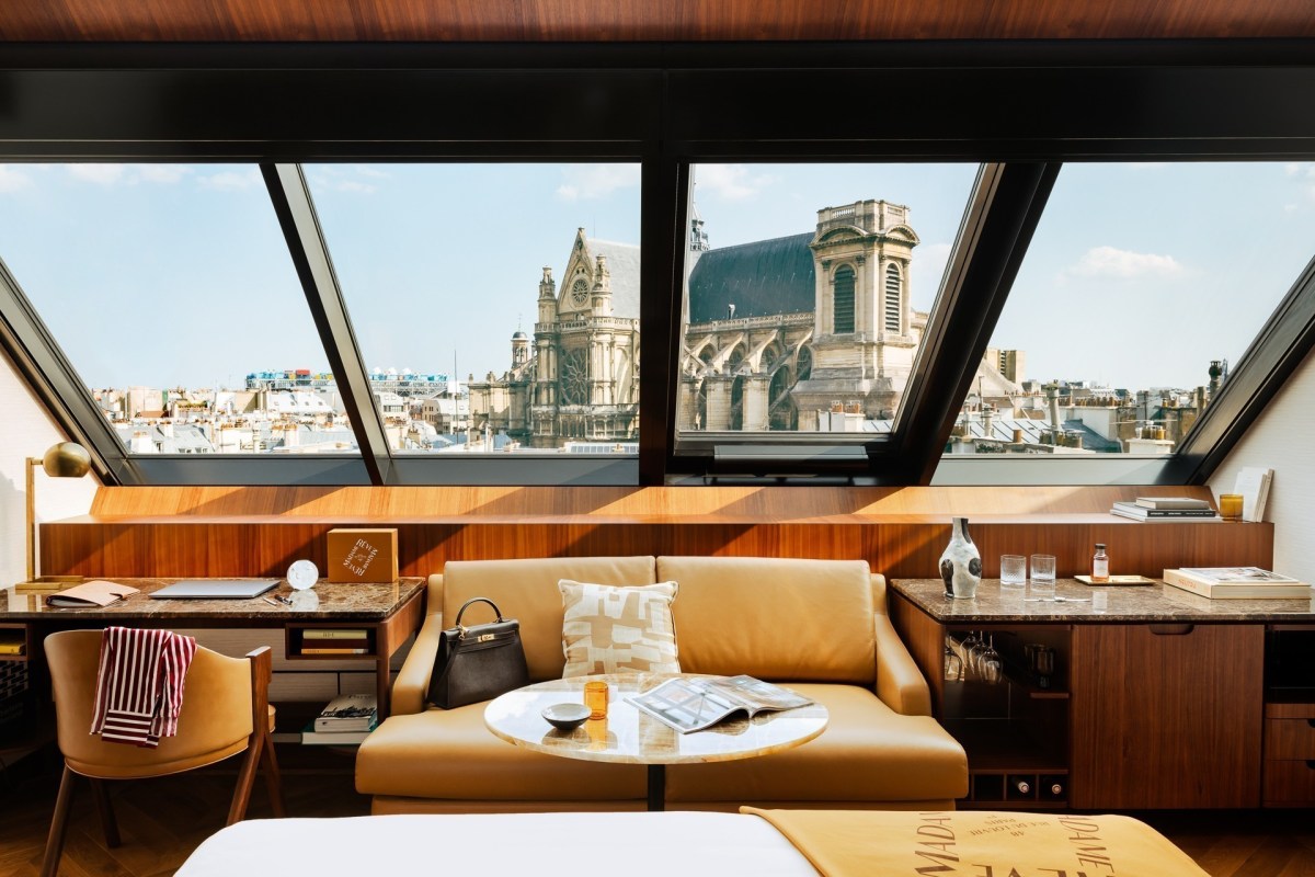 Guest suite seating area with leather sofa and desk, large windows showing Saint-Eustache church