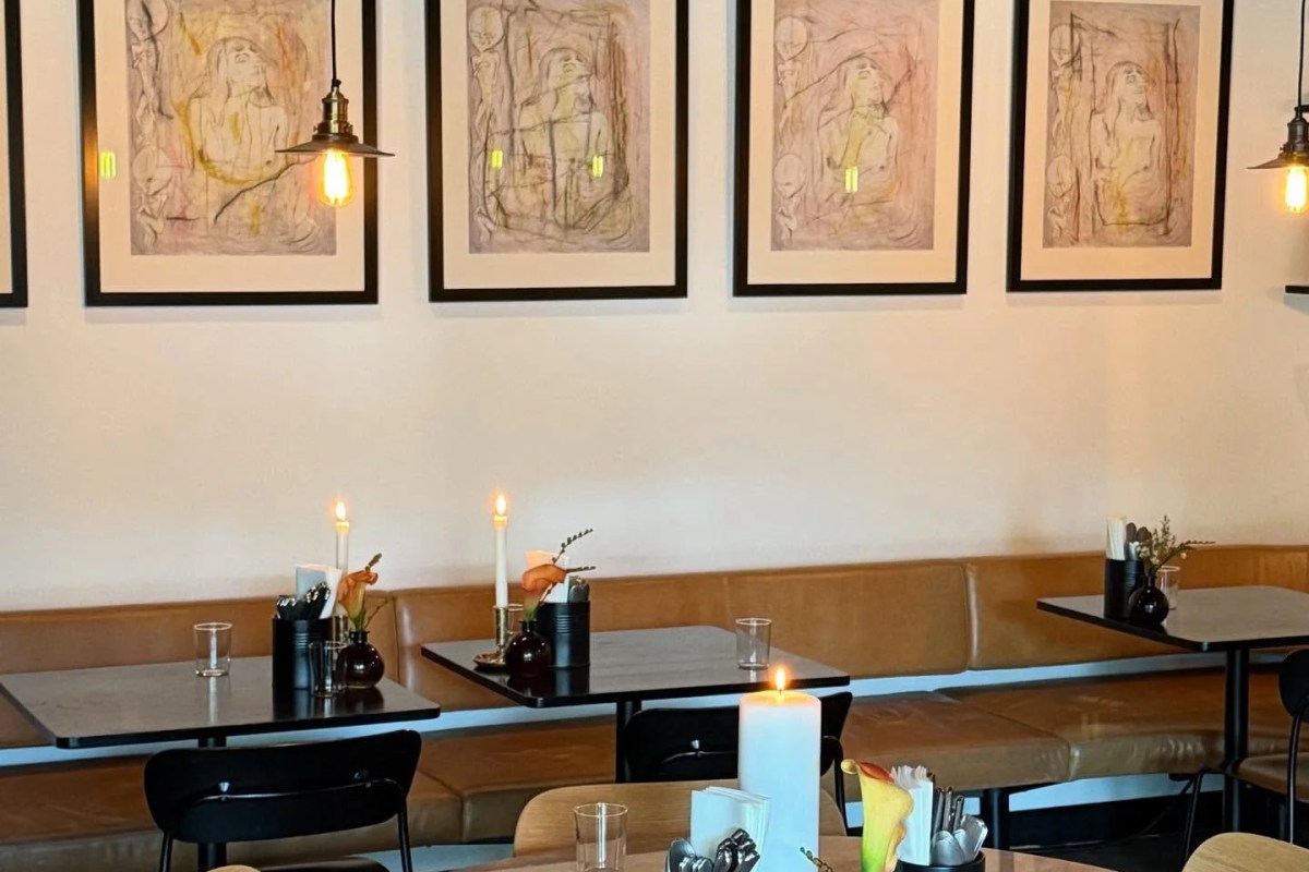 Dining room with leather banquette seating, candlelit tables, and framed artwork on wall