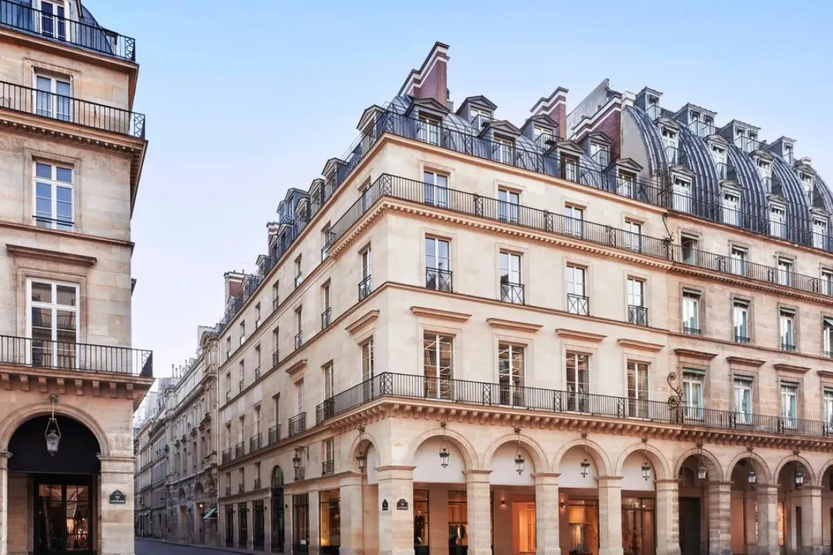 Haussmannian stone facade of the hotel on a Parisian corner street with arched ground-floor arcade