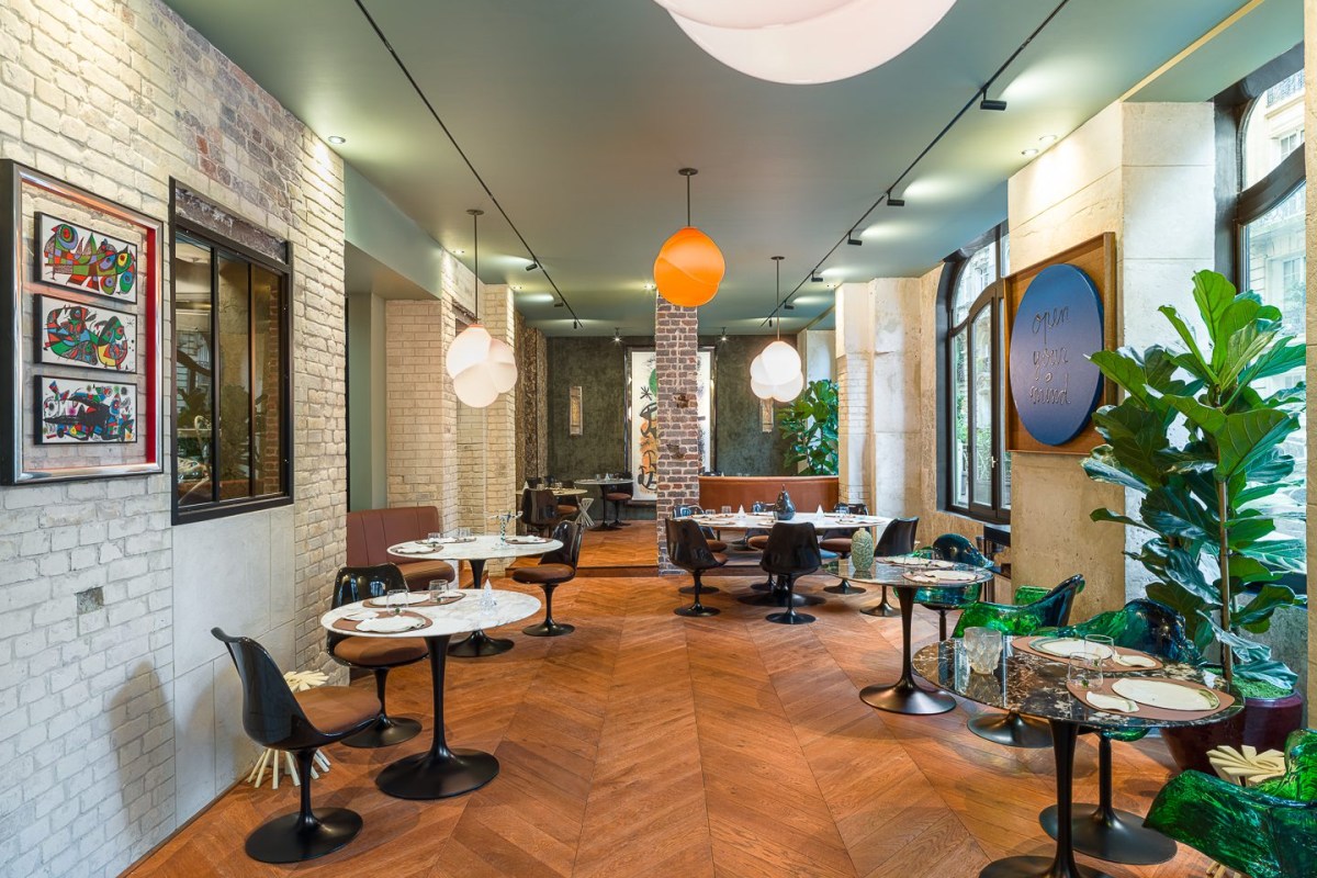 Bright dining room with colorful art, orange pendant lamp and wood chevron floor