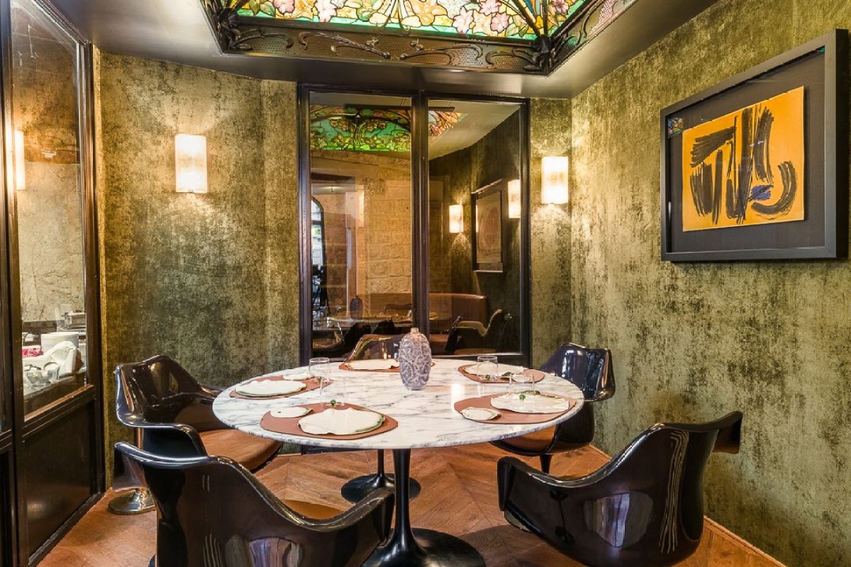 Intimate dining nook with ornate stained-glass ceiling, green velvet walls and marble table