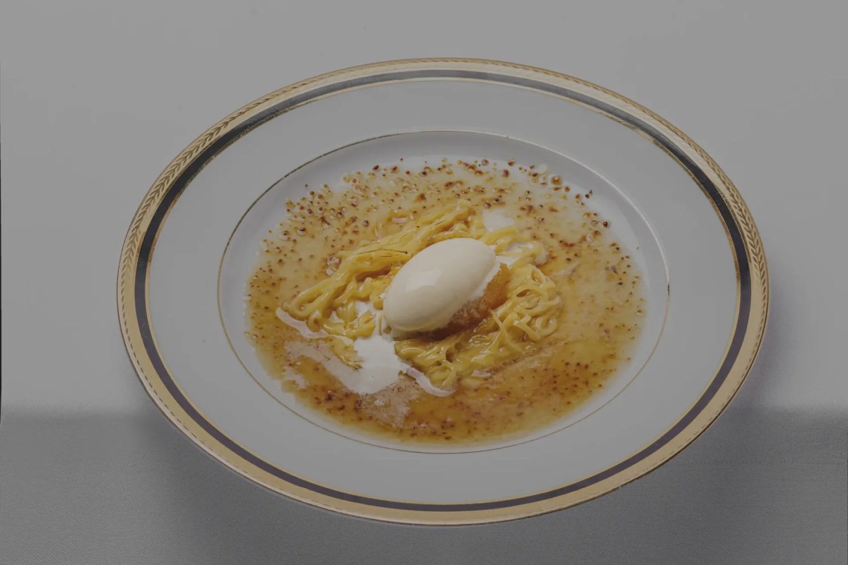 Fine dining dessert plate with caramelized noodle-like strands and a quenelle of cream on gold-rimmed china.