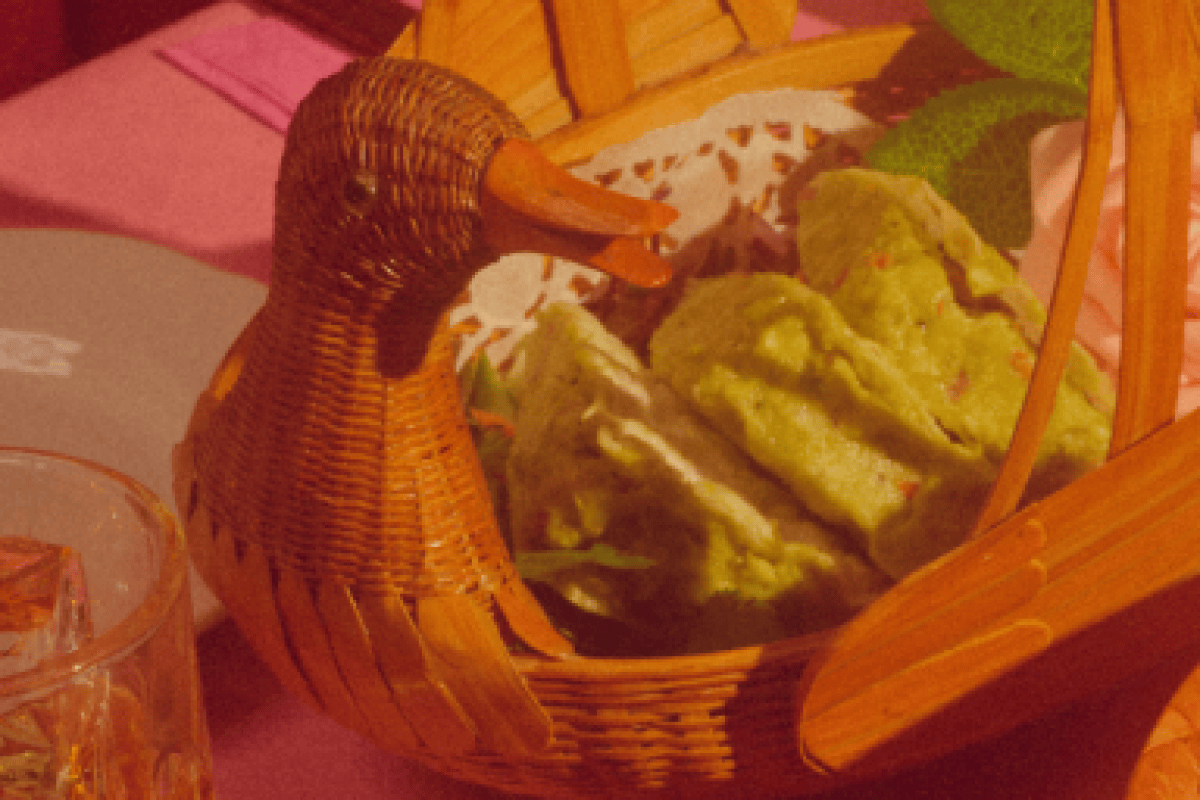 Basket shaped like a duck holding rolled green dumplings or wraps on a table
