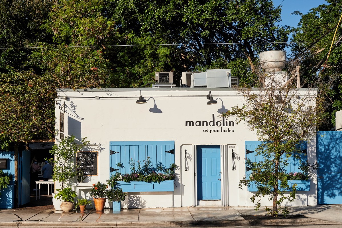Exterior of Mandolin Aegean Bistro, white building with blue shutters and door, storefront sign