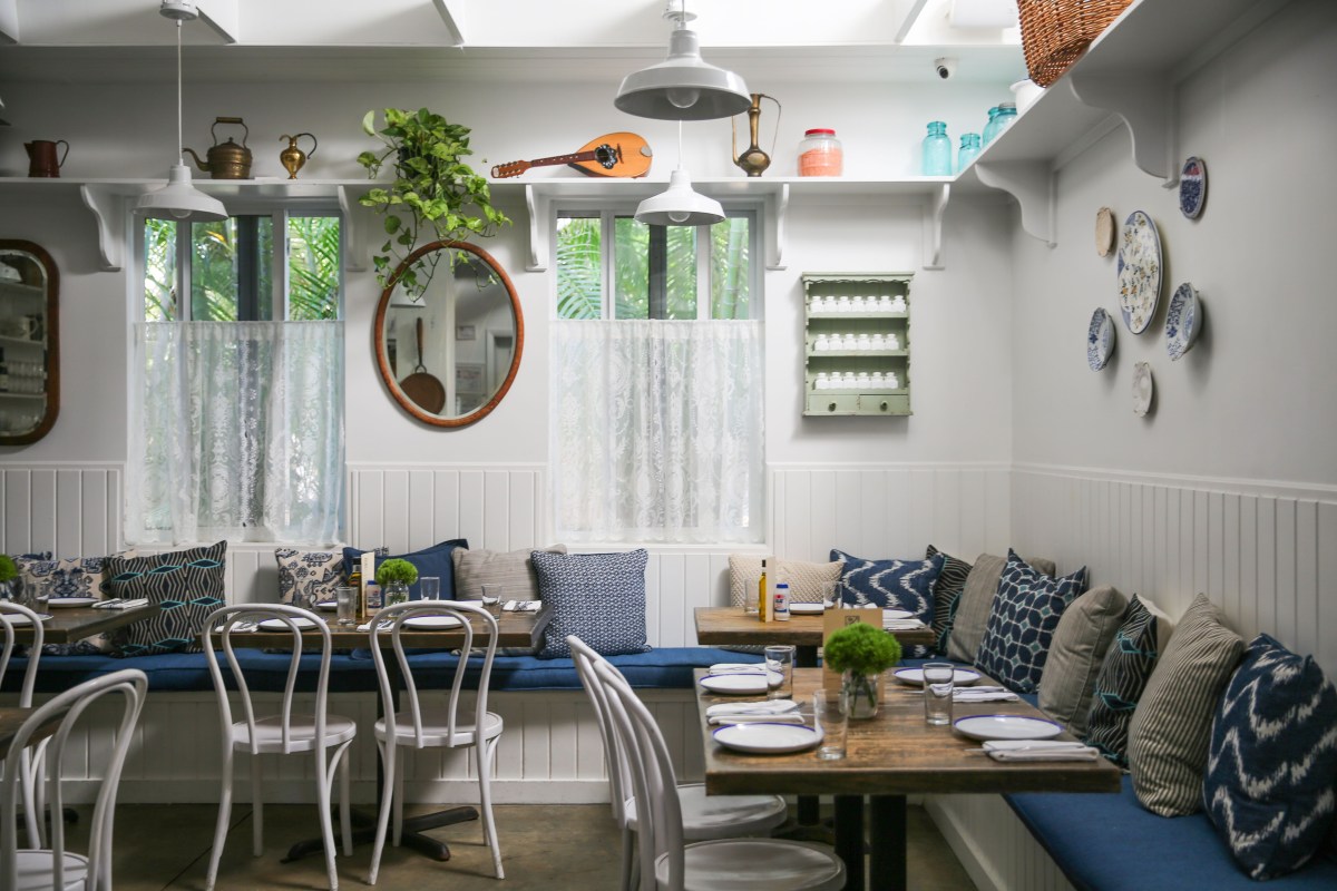 Cozy interior dining room with blue striped banquette seating and Greek-inspired decor