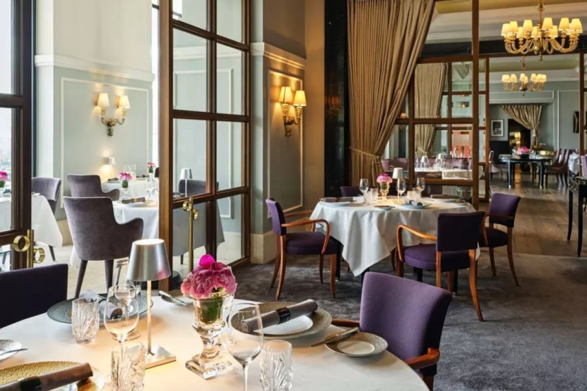 Elegant dining room with purple velvet chairs, white-clothed tables and chandeliers